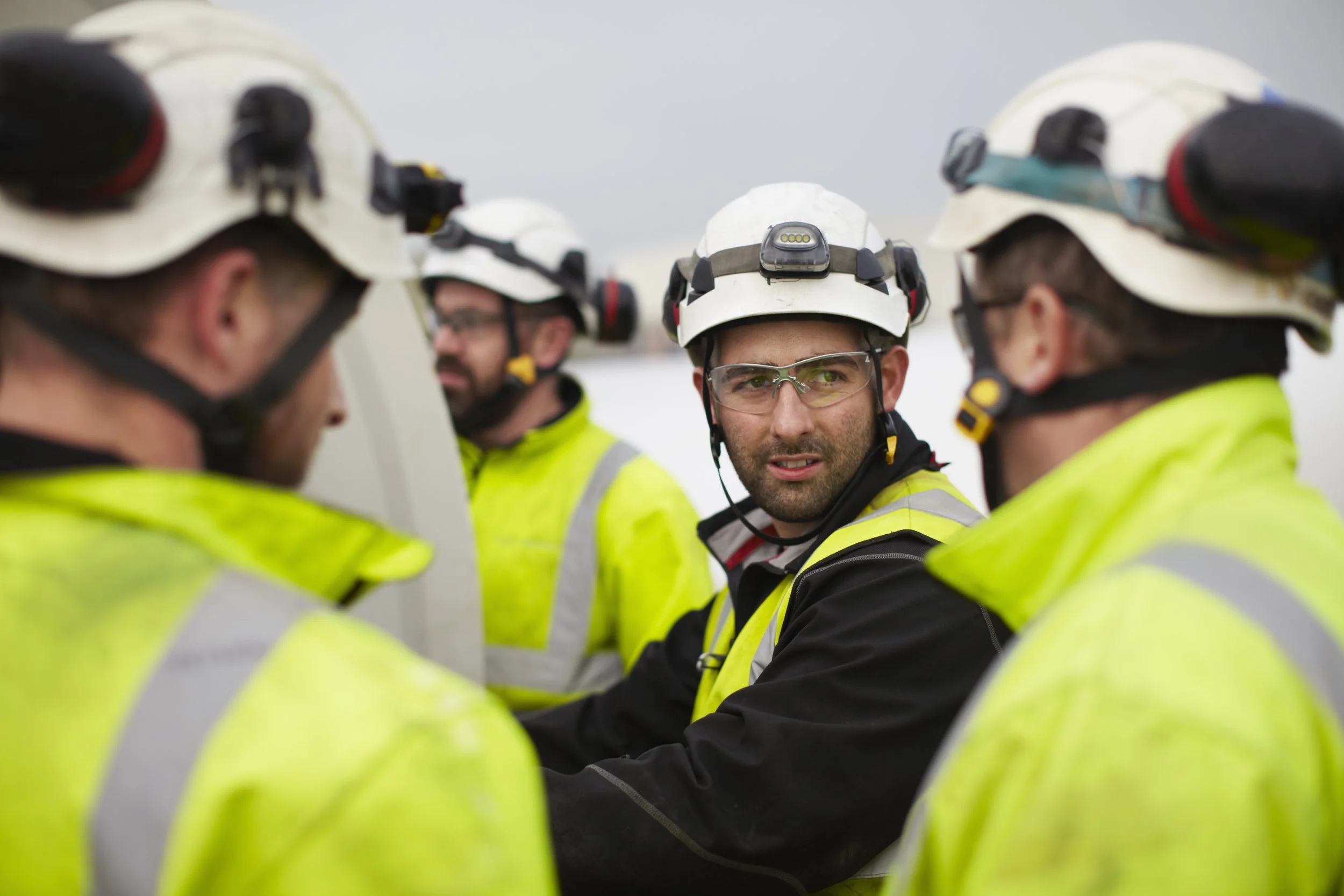 Construction workers wearing hard hats and reflective jackets having a discussion.