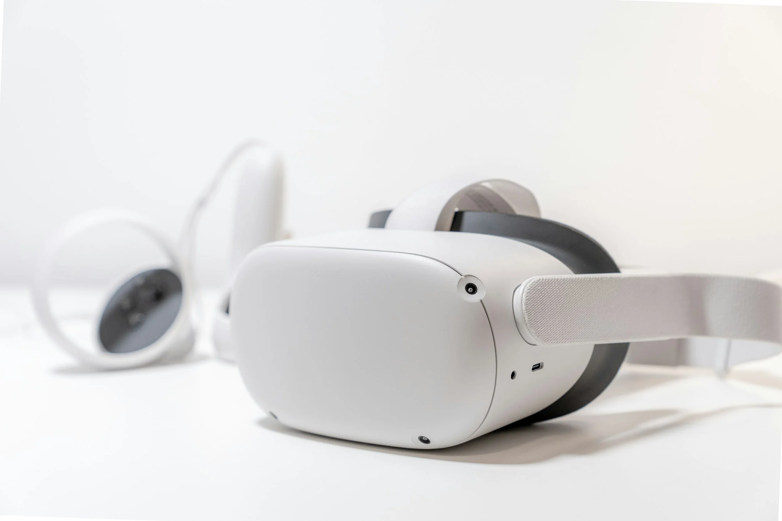 White virtual reality headset and controllers on a white surface.