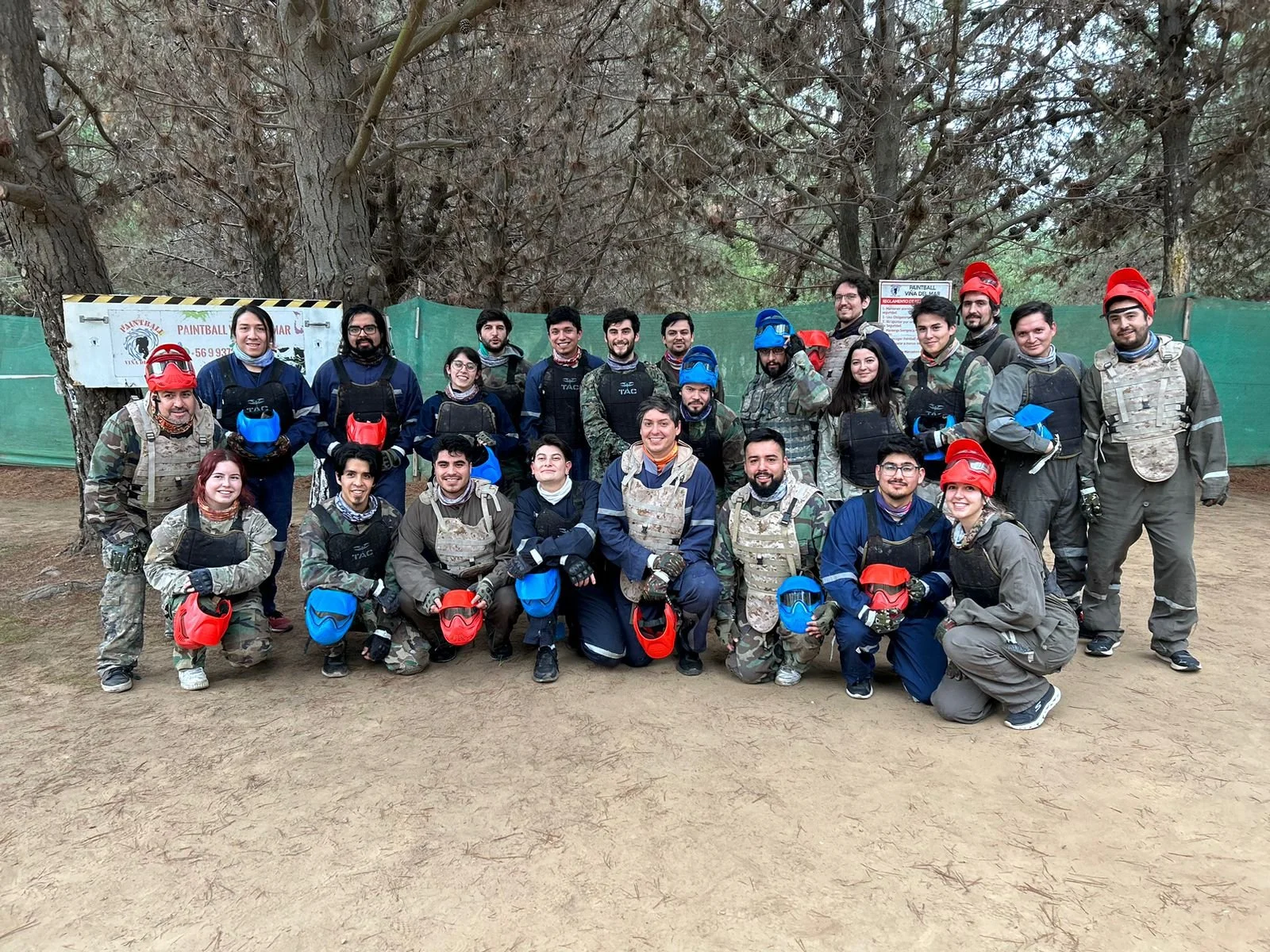 Group of Yoy team members wearing paintball gear outdoors, holding helmets, and posing for a photo.