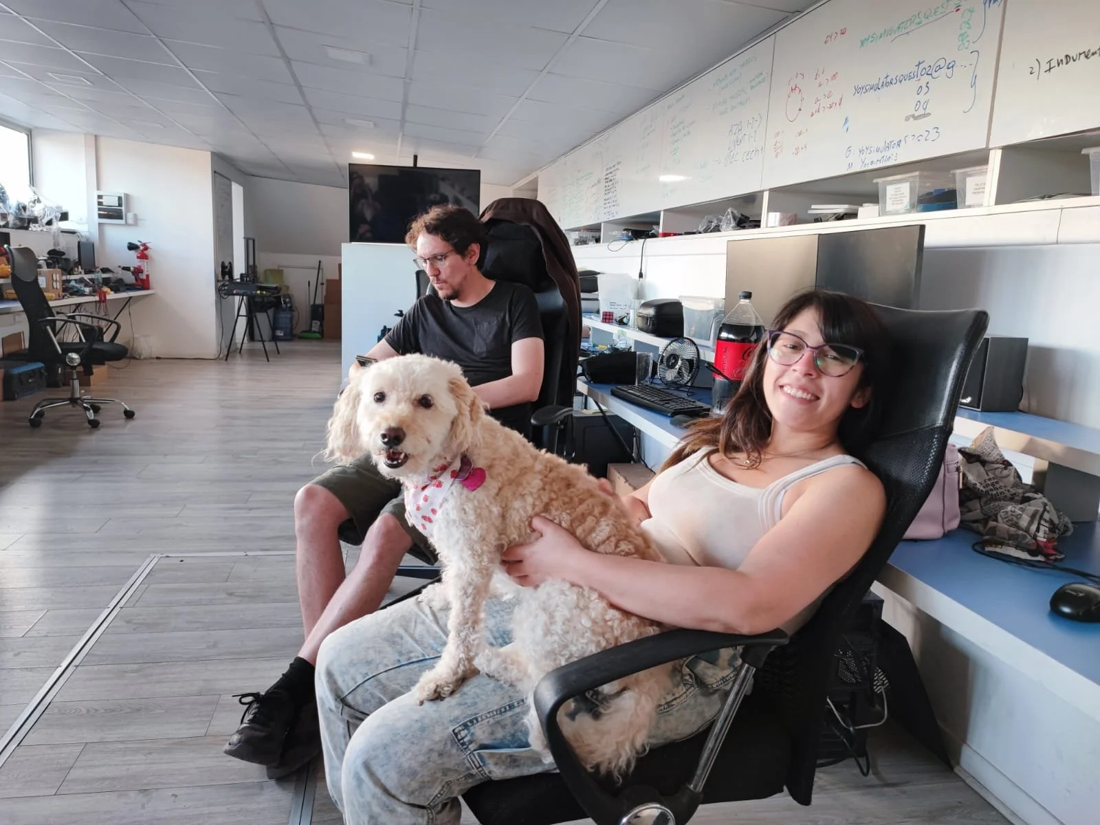 Office scene with two Yoy team members sitting on chairs; one holding a dog.